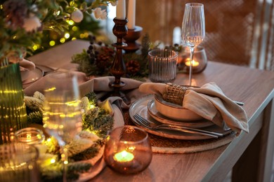 Photo of Christmas place setting with festive decor on wooden table in room