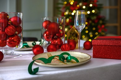 Photo of Christmas place setting with festive decor on table in room, closeup