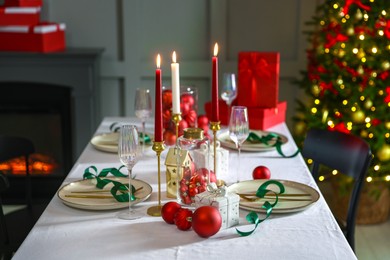 Photo of Christmas place setting with festive decor on table in room