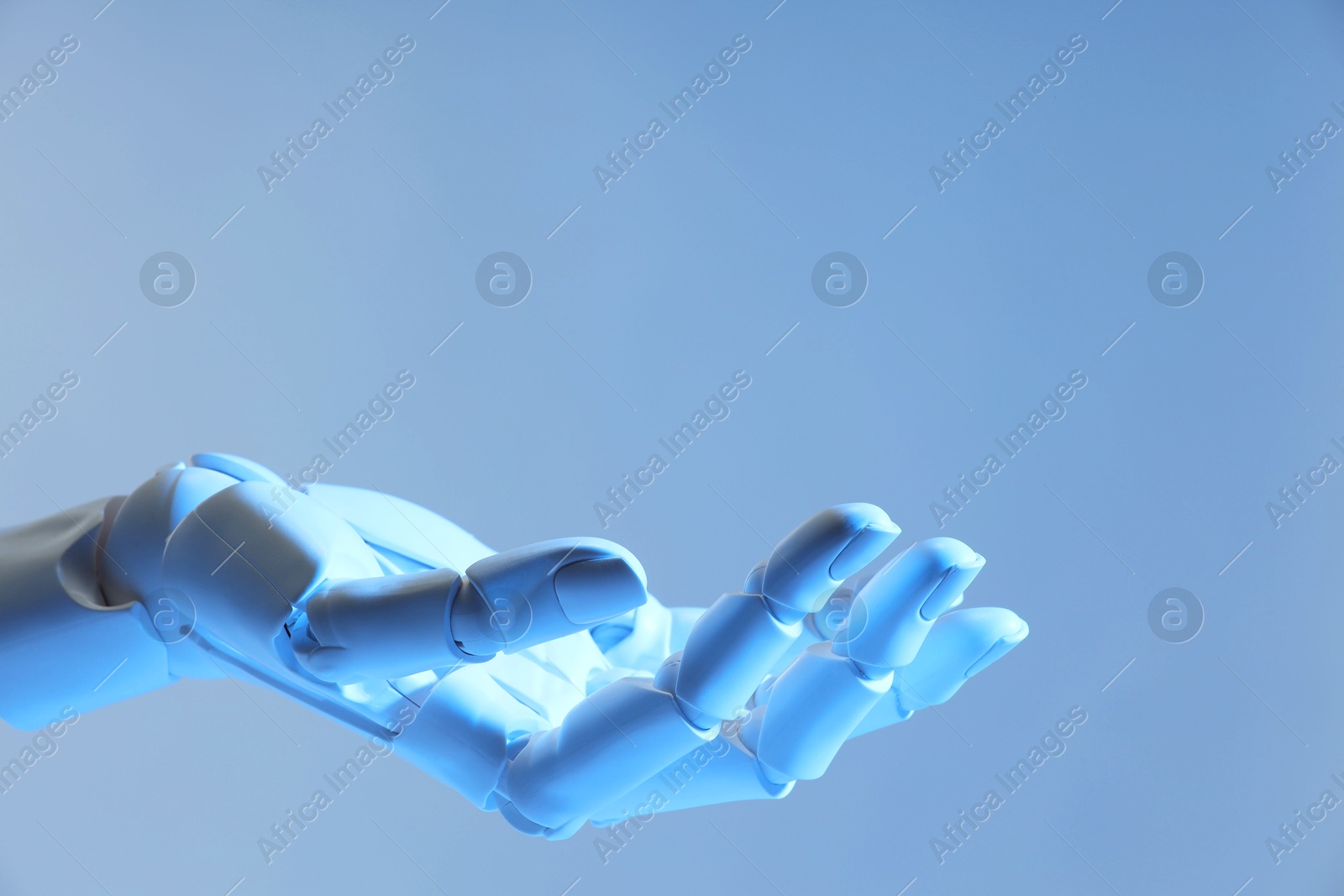 Photo of Artificial intelligence. Robot hand gesturing on pale light blue background