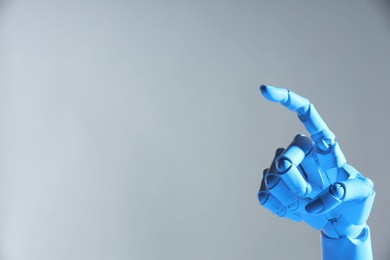 Photo of Artificial intelligence. Robot hand pointing at something on grey background, space for text