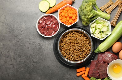 Photo of Dry pet food and natural products on grey table, top view. Space for text