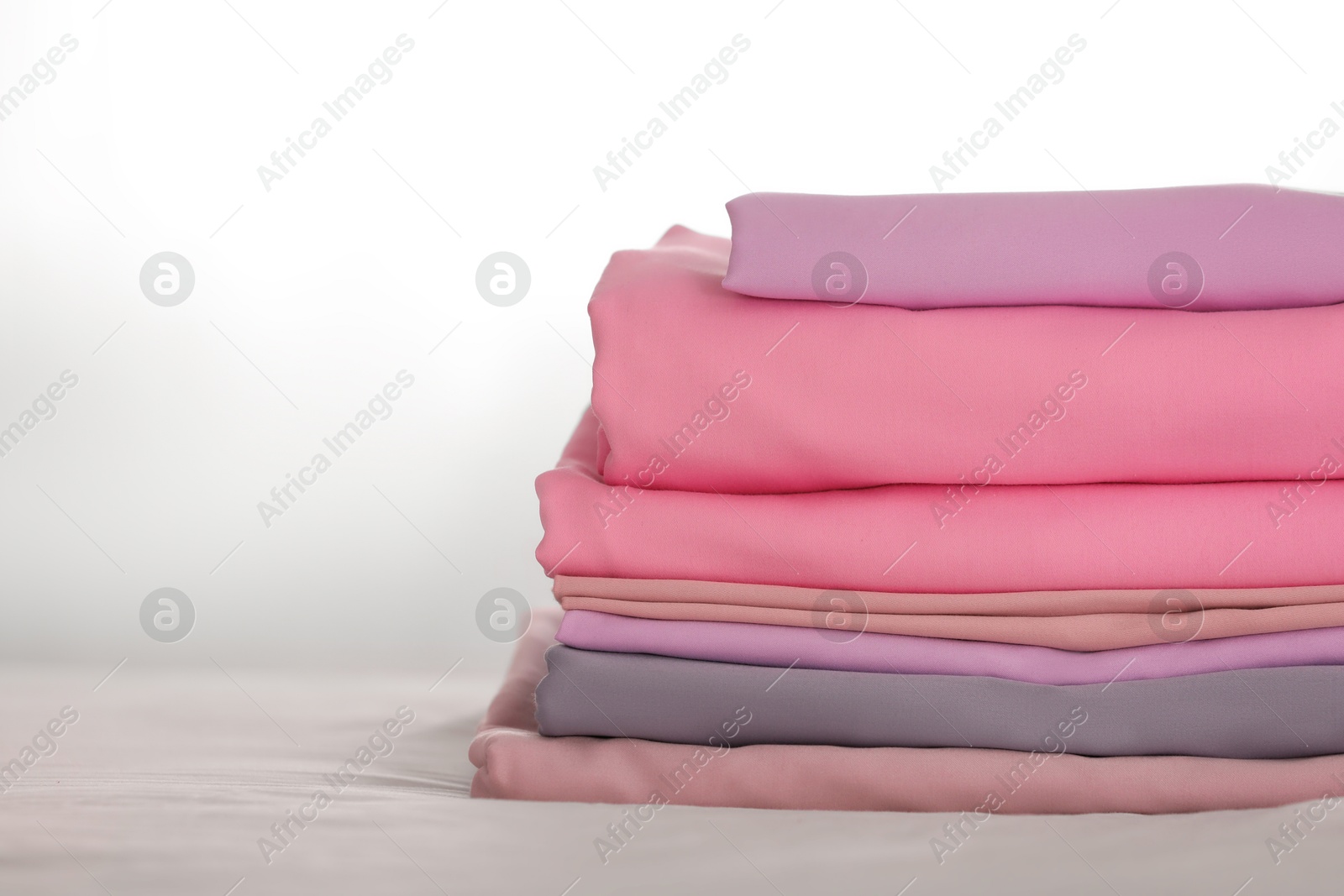 Photo of Stack of clean color folded linens on bed. Space for text