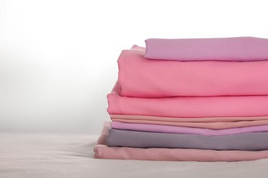 Photo of Stack of clean color folded linens on bed. Space for text