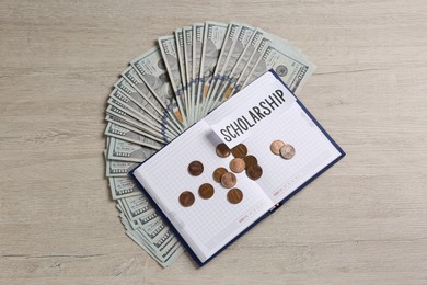 Photo of Paper with word Scholarship, notebook, banknotes and coins on wooden table, flat lay