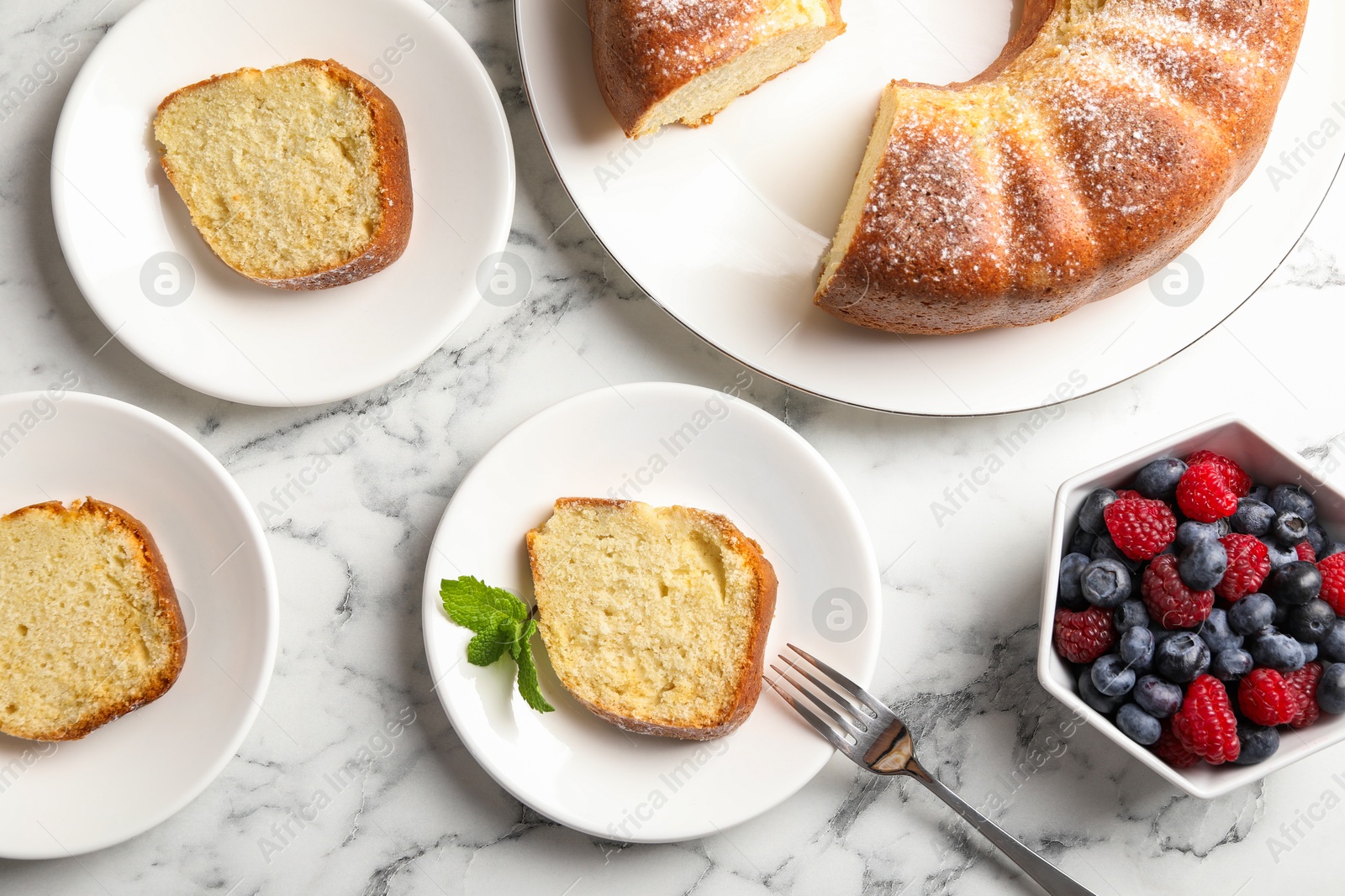 Photo of Freshly baked sponge cake, mint and berries on white marble table, top view