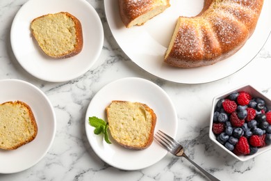 Photo of Freshly baked sponge cake, mint and berries on white marble table, top view