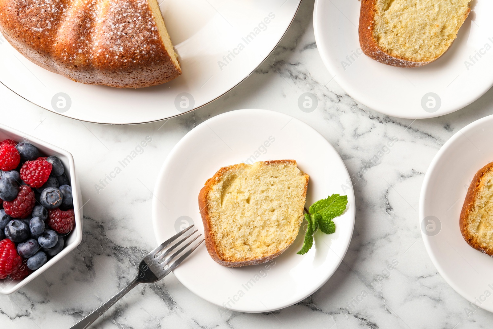 Photo of Freshly baked sponge cake, mint and berries on white marble table, top view