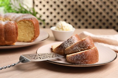 Photo of Pieces of freshly baked sponge cake, server and ice cream on wooden table, closeup