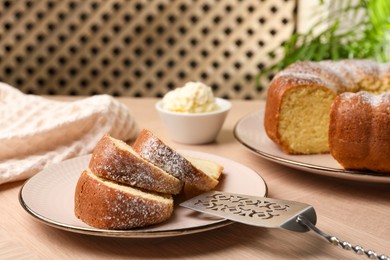 Photo of Pieces of freshly baked sponge cake, server and ice cream on wooden table, closeup