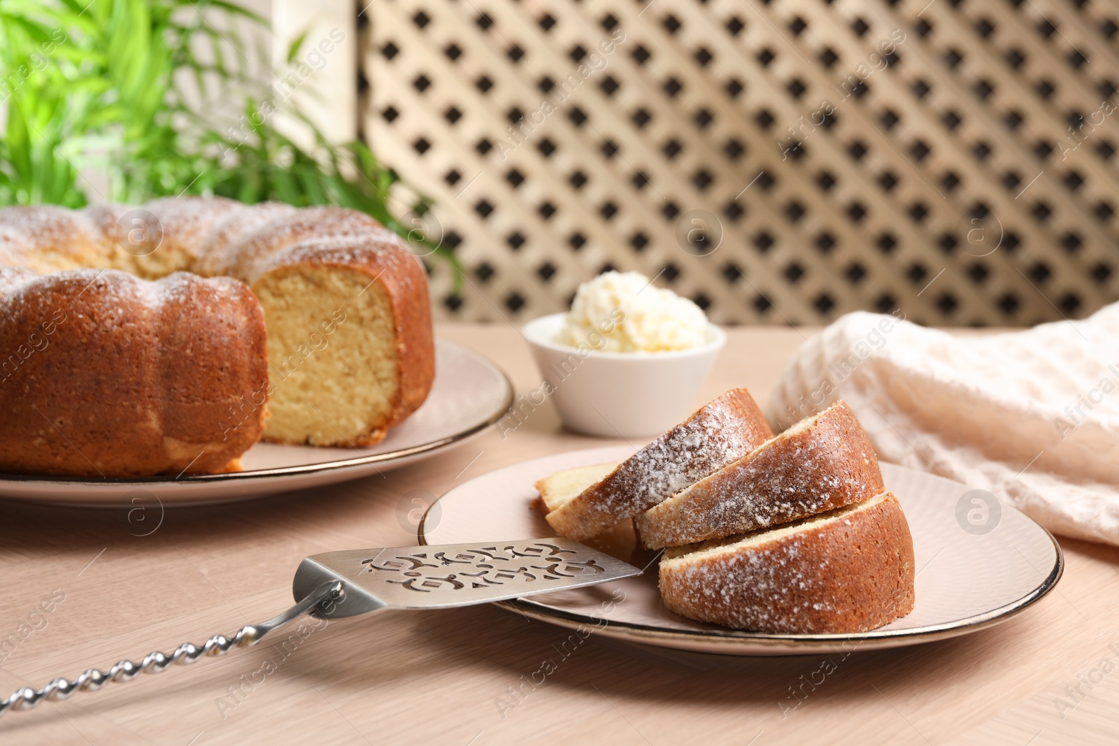 Photo of Pieces of freshly baked sponge cake, server and ice cream on wooden table