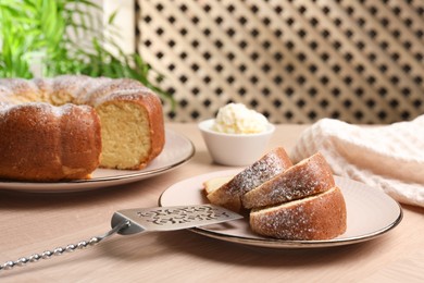 Photo of Pieces of freshly baked sponge cake, server and ice cream on wooden table