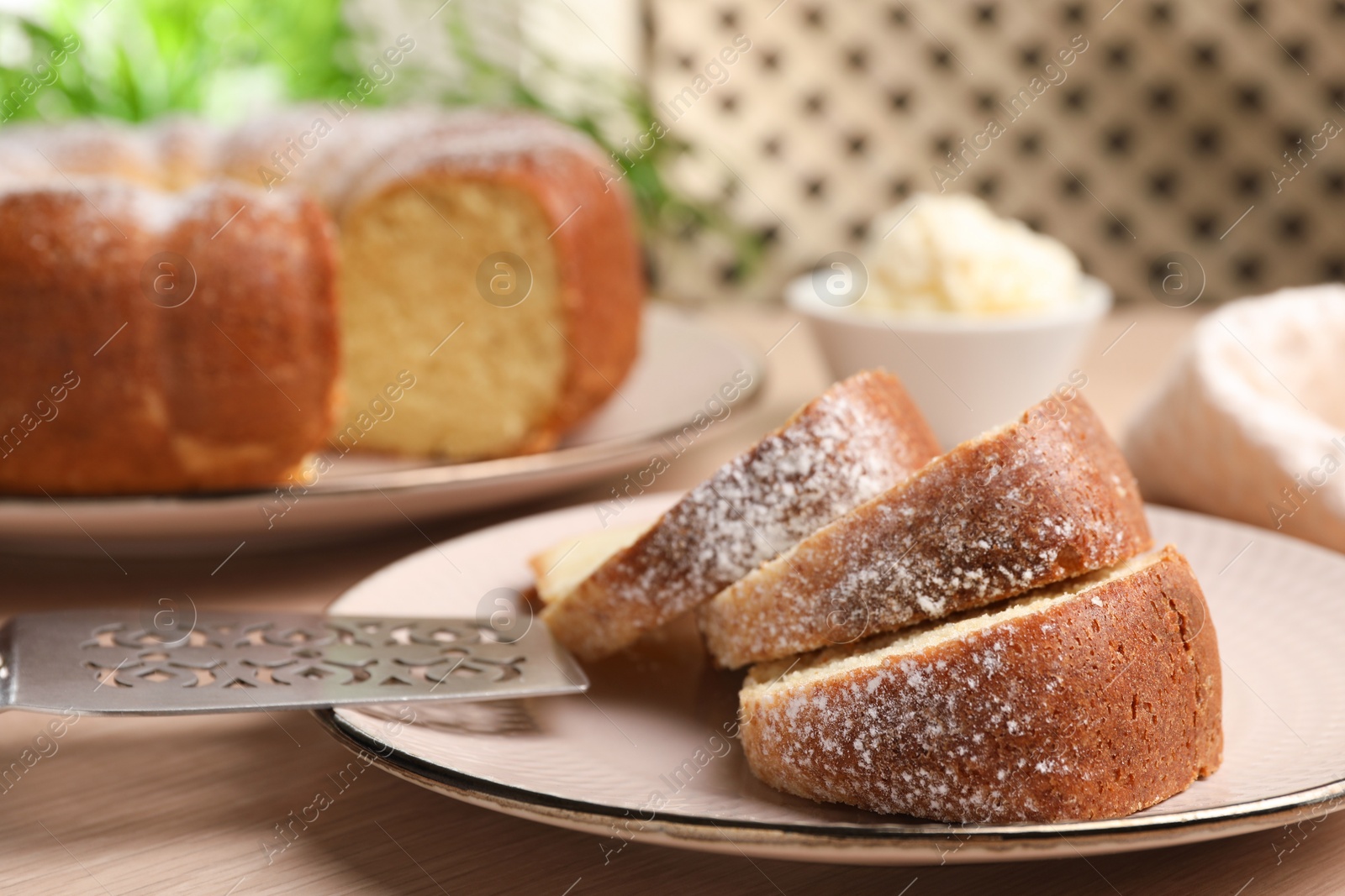 Photo of Pieces of freshly baked sponge cake, server and ice cream on wooden table, closeup