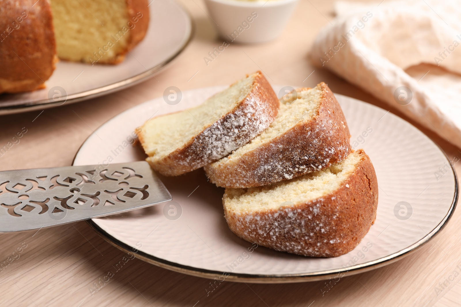 Photo of Pieces of freshly baked sponge cake and server on wooden table, closeup