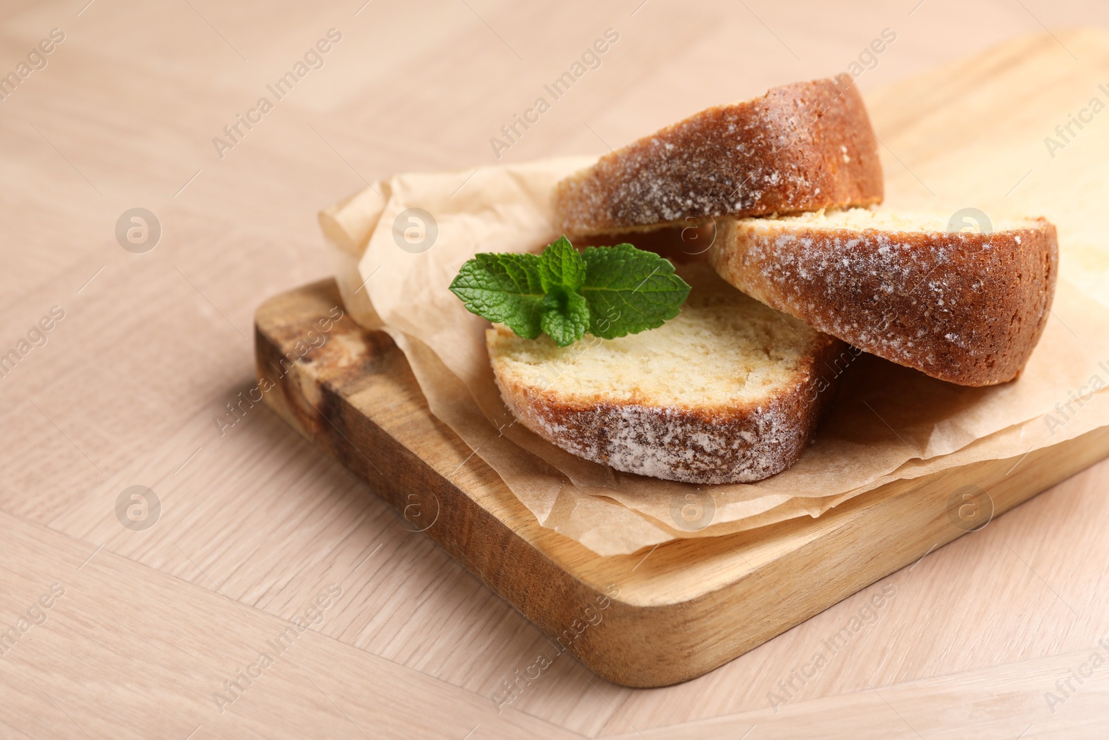 Photo of Pieces of freshly baked sponge cake and mint on wooden table, closeup