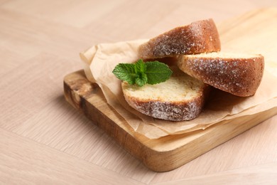 Photo of Pieces of freshly baked sponge cake and mint on wooden table, closeup