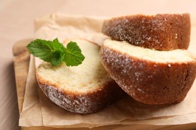 Photo of Pieces of freshly baked sponge cake and mint on table, closeup