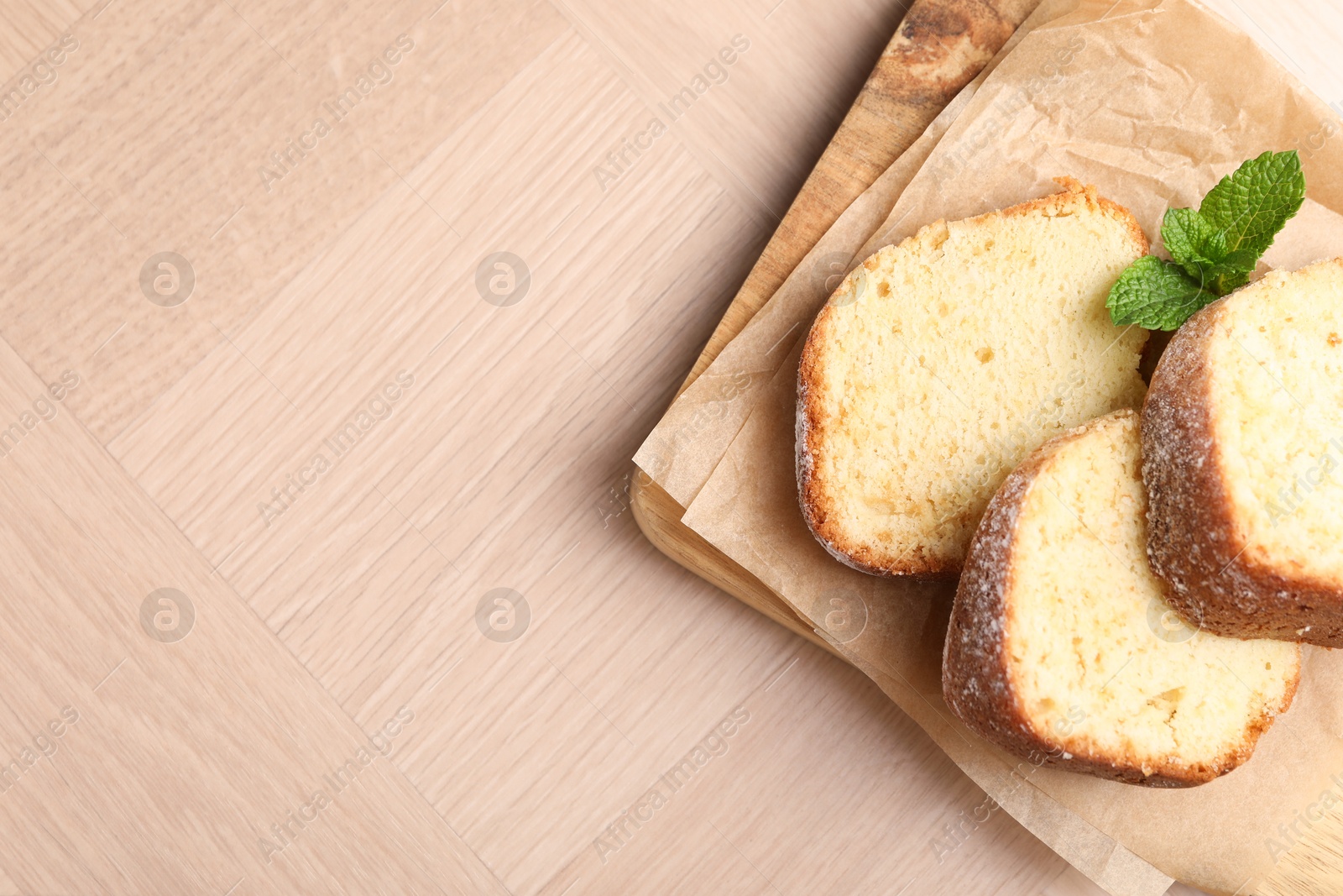 Photo of Pieces of freshly baked sponge cake and mint on wooden table, top view. Space for text