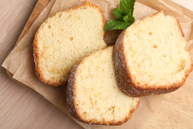 Photo of Pieces of freshly baked sponge cake and mint on wooden table, top view