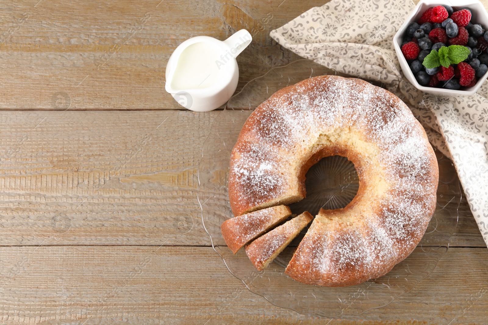 Photo of Freshly baked sponge cake, milk and berries on wooden table, top view. Space for text