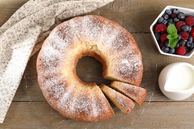 Photo of Freshly baked sponge cake, milk and berries on wooden table, top view