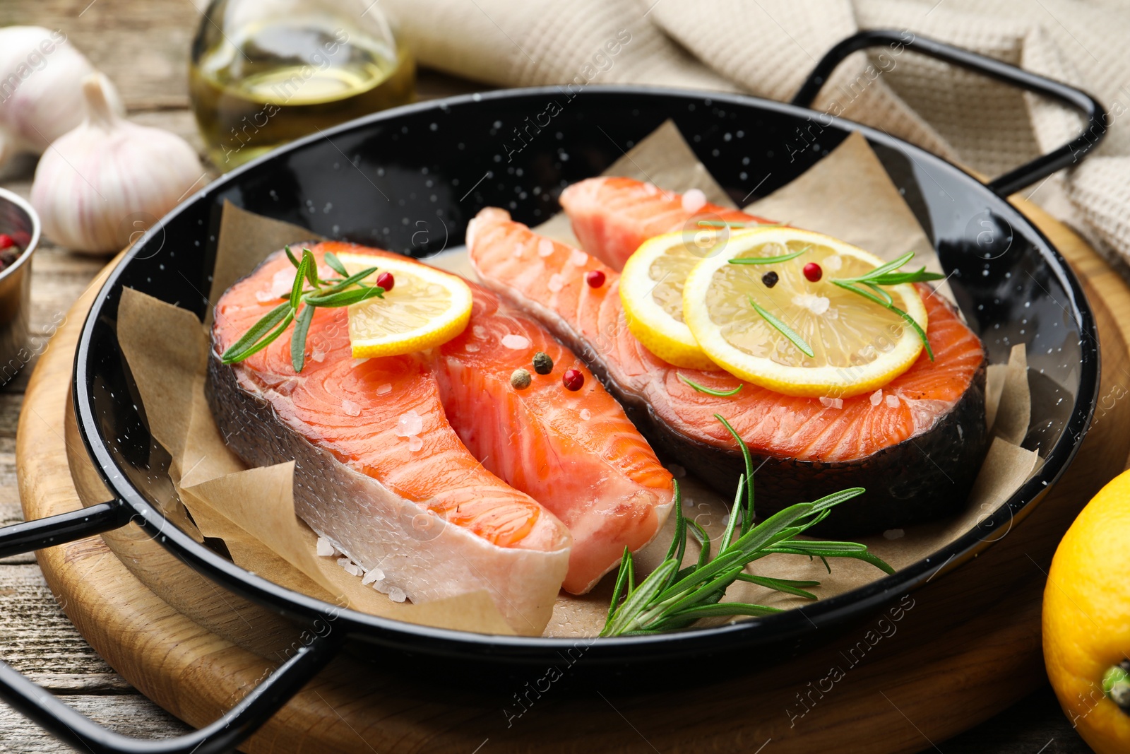 Photo of Fresh raw salmon steaks with spices in pan on wooden table, closeup