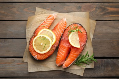 Photo of Fresh raw salmon steaks with rosemary and lemon on wooden table, top view