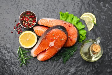 Photo of Fresh raw salmon steaks with spices and products on dark textured table, flat lay