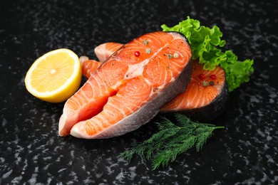 Photo of Fresh raw salmon steaks with spices, lemon, lettuce and dill on dark textured table, closeup