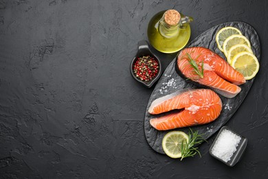 Photo of Fresh raw salmon steaks with salt, lemon, oil, peppercorns and rosemary on dark textured table, flat lay. Space for text