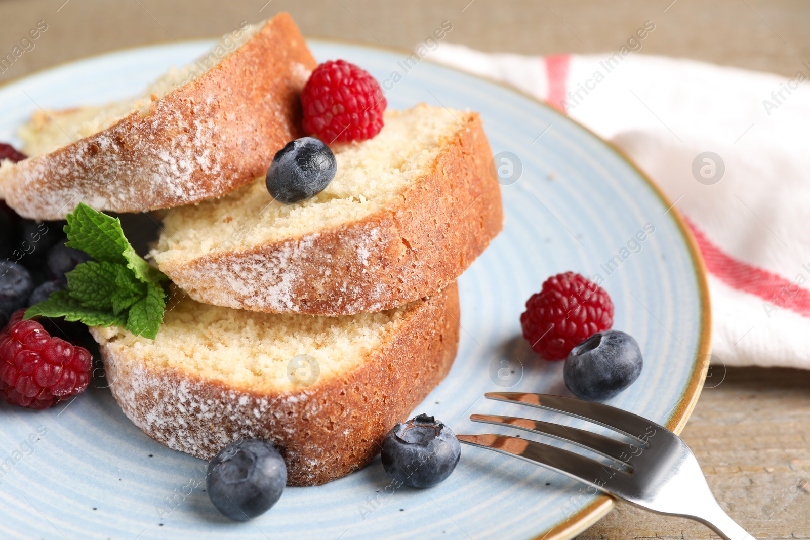 Photo of Pieces of freshly baked sponge cake and berries on table, closeup