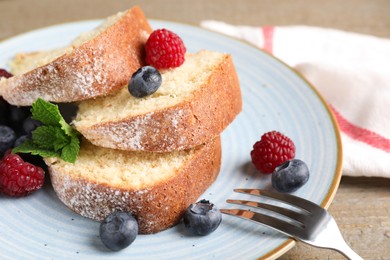 Photo of Pieces of freshly baked sponge cake and berries on table, closeup