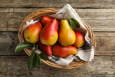 Photo of Ripe juicy pears in wicker basket on wooden table, top view