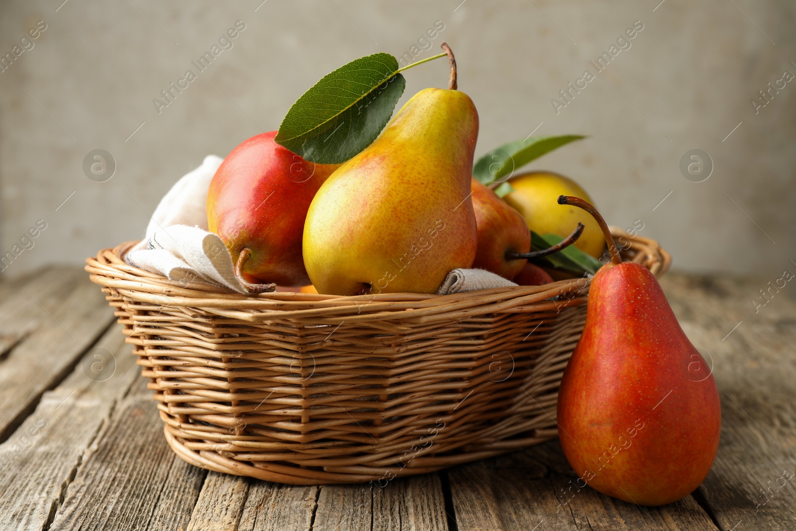 Photo of Ripe juicy pears in wicker basket on wooden table