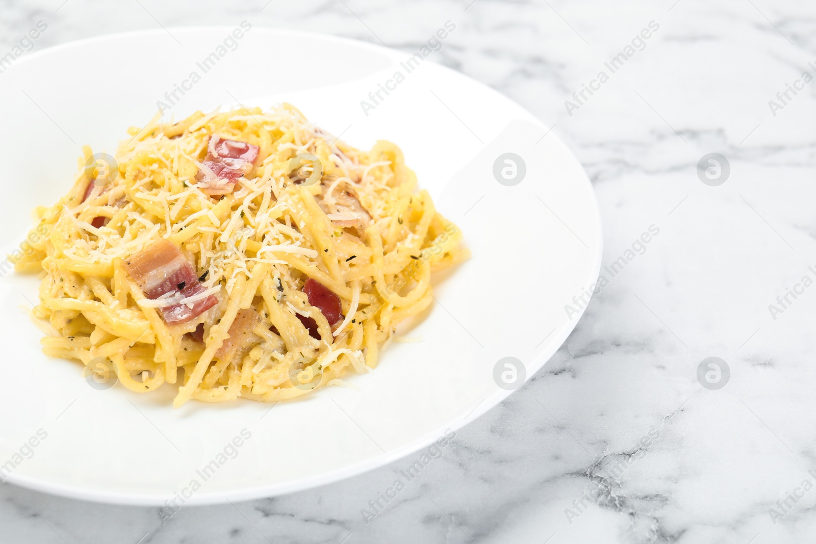 Photo of Delicious pasta Carbonara with bacon on white marble table, closeup