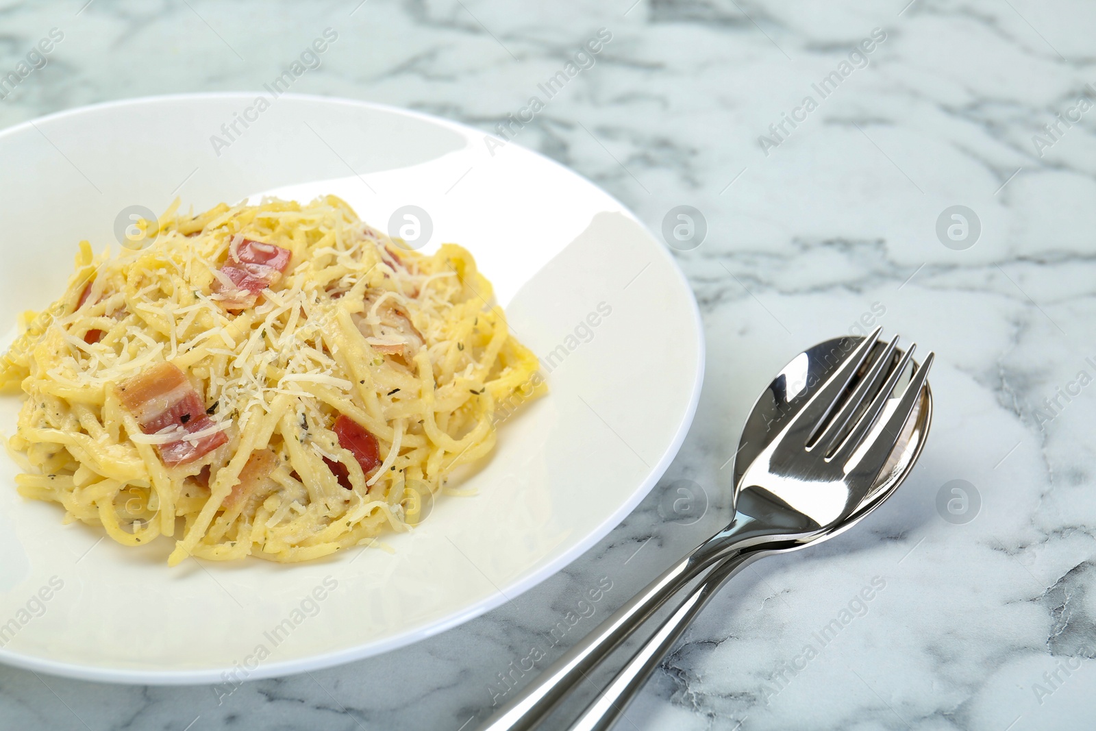 Photo of Delicious pasta Carbonara with bacon served on white marble table, closeup