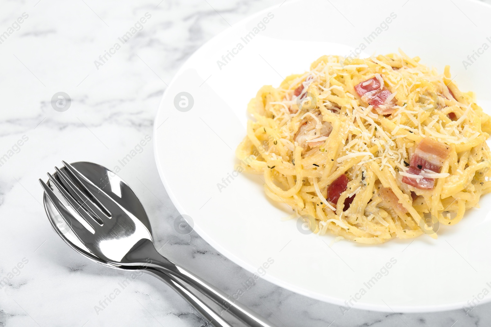 Photo of Delicious pasta Carbonara with bacon served on white marble table, closeup