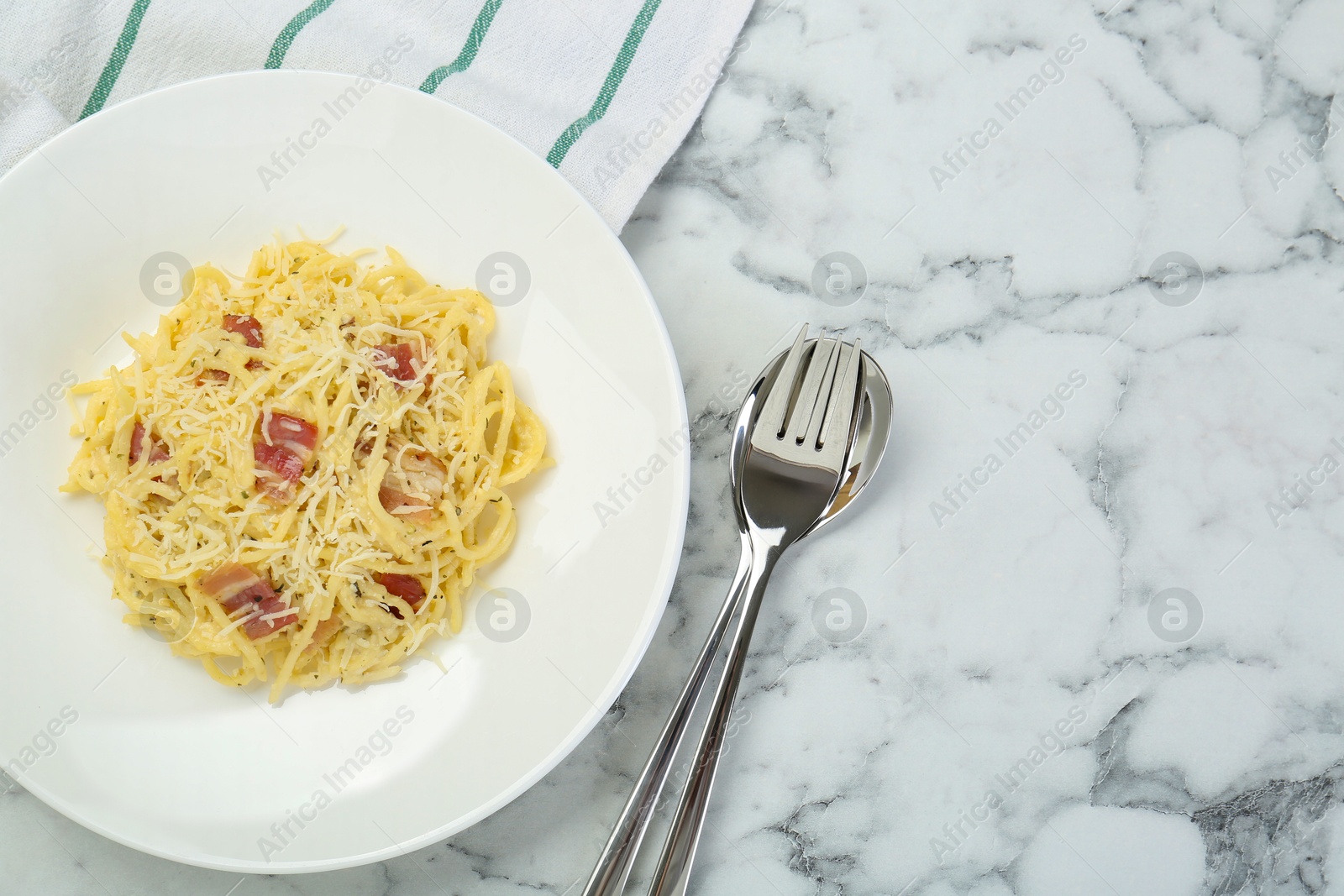 Photo of Delicious pasta Carbonara with bacon served on white marble table, flat lay. Space for text