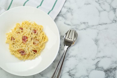 Photo of Delicious pasta Carbonara with bacon served on white marble table, flat lay. Space for text