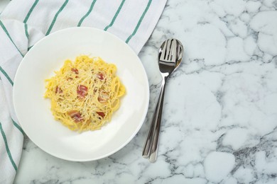 Photo of Delicious pasta Carbonara with bacon served on white marble table, flat lay. Space for text