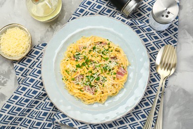 Photo of Delicious pasta Carbonara with bacon served on gray textured table, flat lay