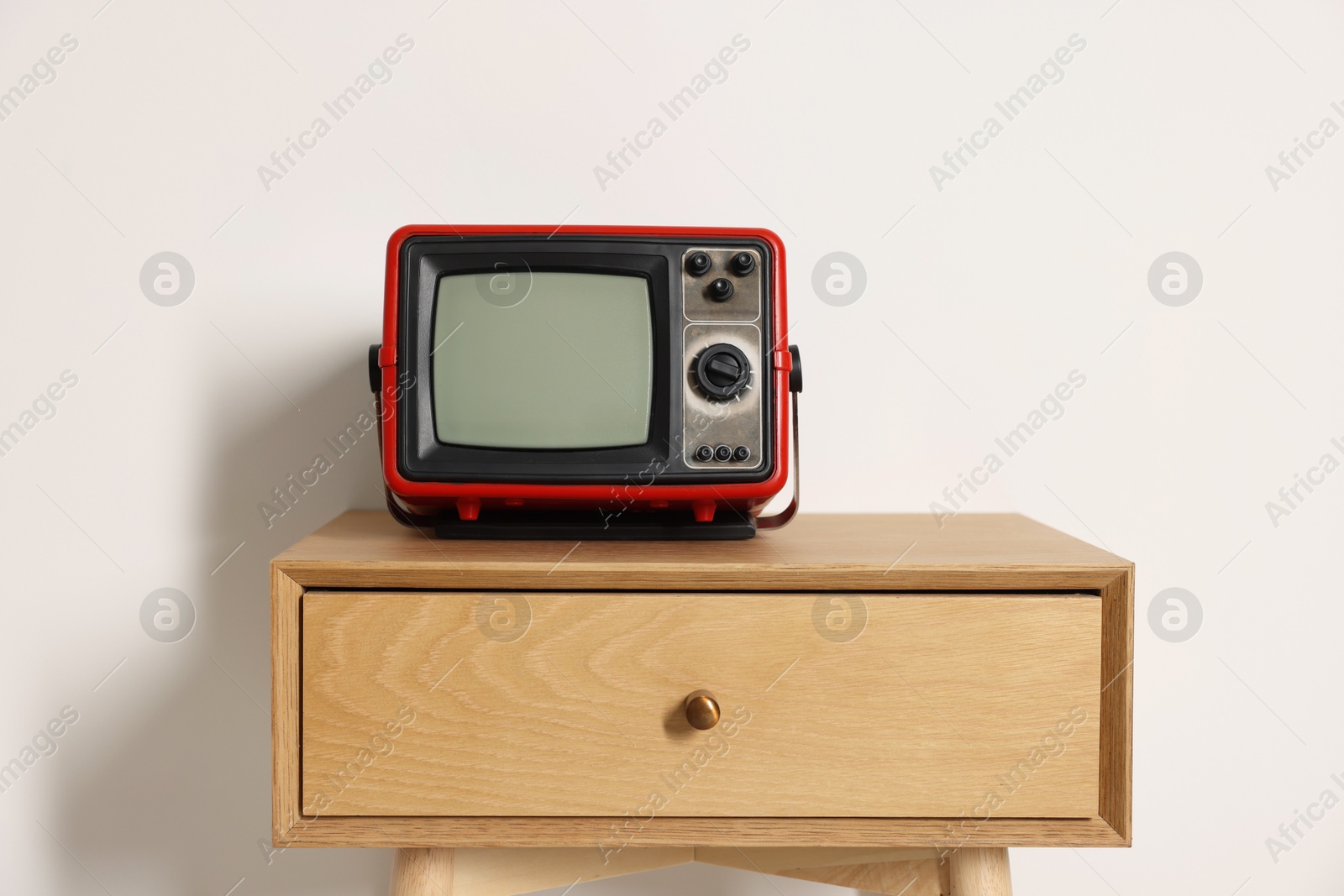 Photo of Retro tv set on nightstand against white wall