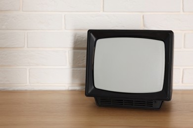 Photo of Retro tv set on wooden shelf against white brick wall. Space for text