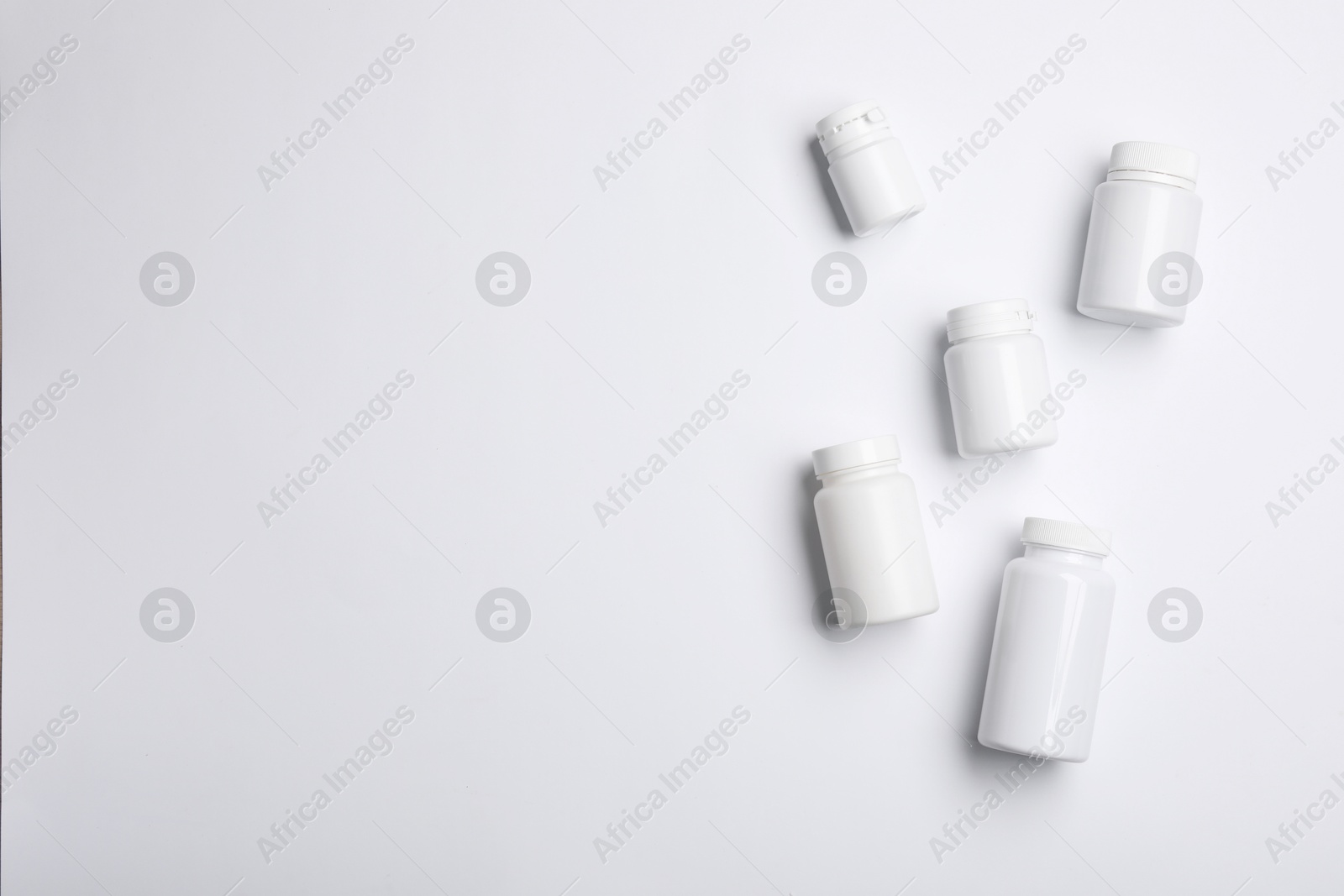 Photo of Many plastic medical bottles on white background, top view. Space for text