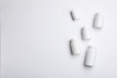 Photo of Many plastic medical bottles on white background, top view. Space for text