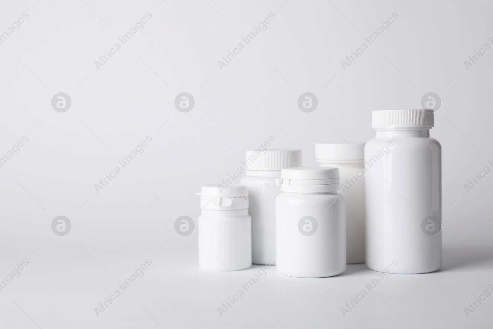 Photo of Many plastic medical bottles on white background, space for text