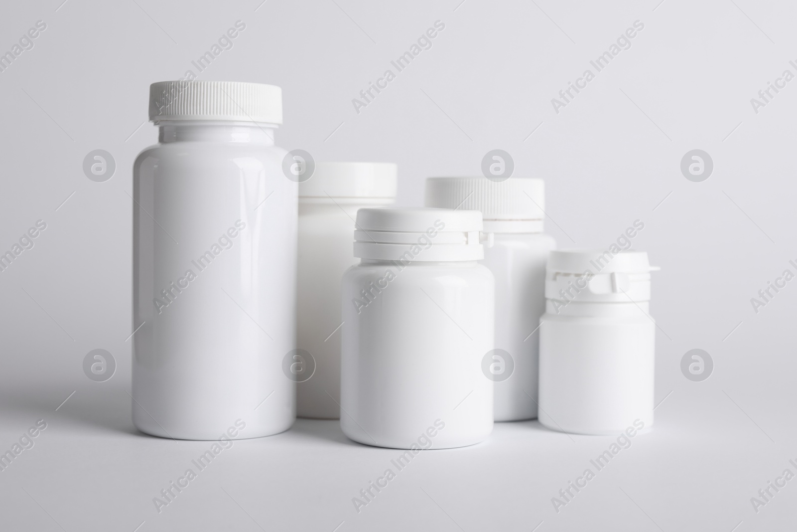 Photo of Many plastic medical bottles on white background