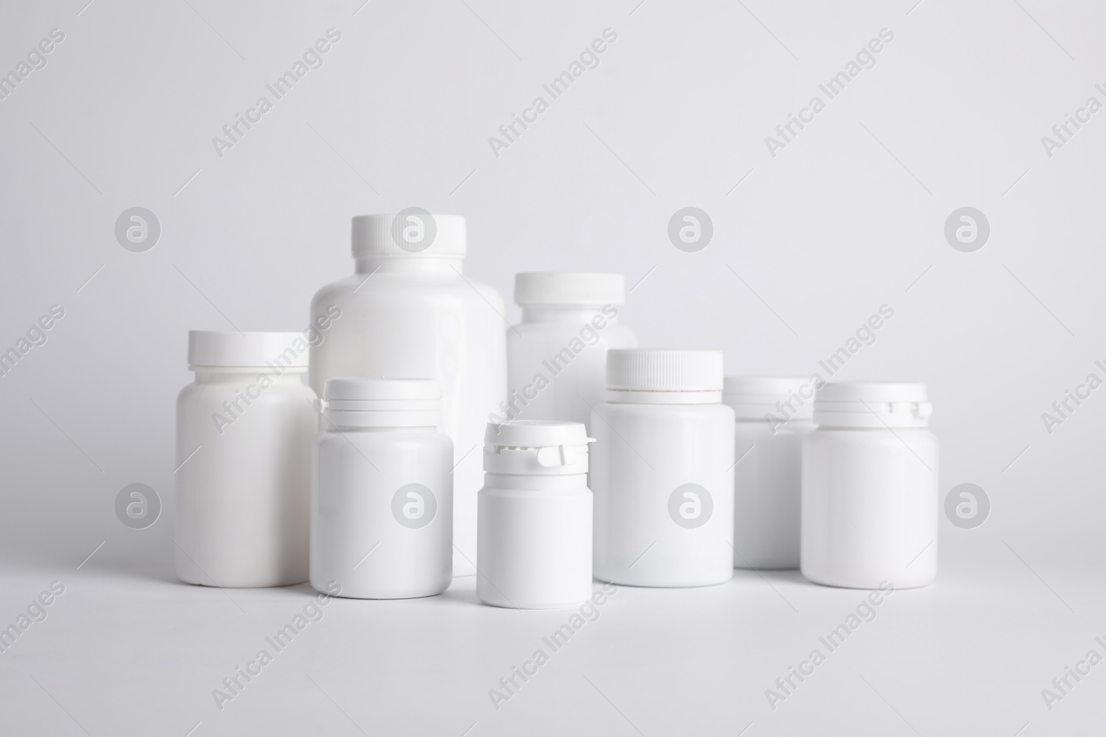 Photo of Many plastic medical bottles on white background