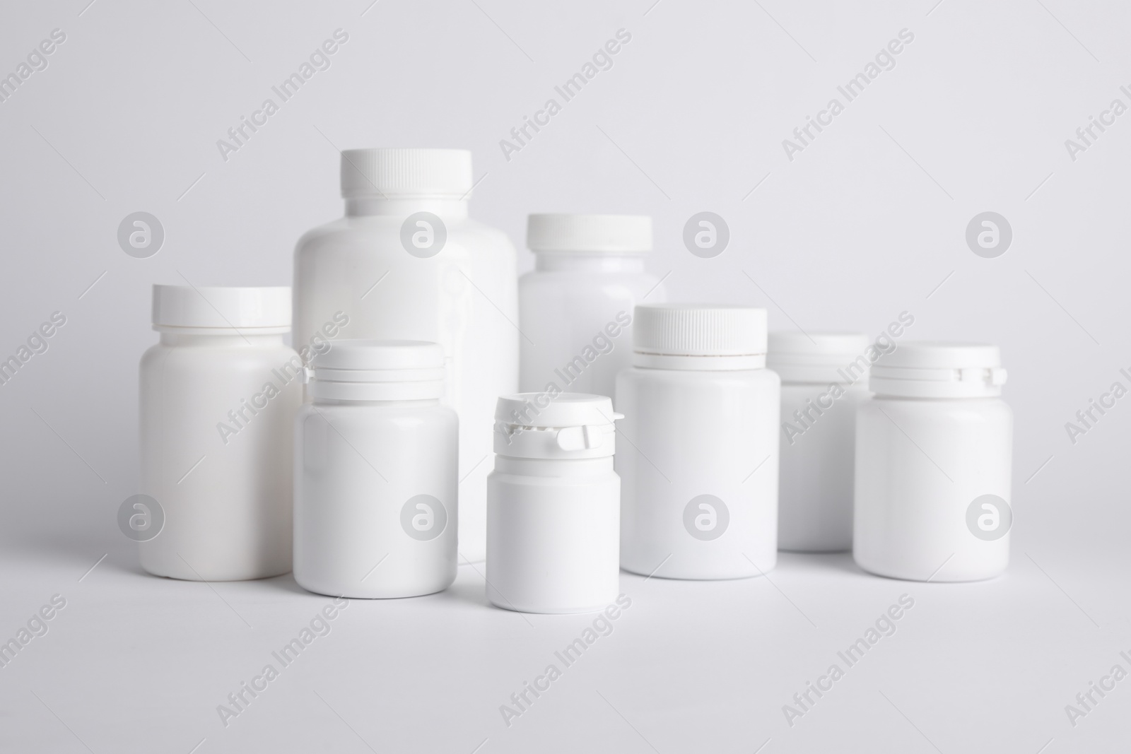 Photo of Many plastic medical bottles on white background