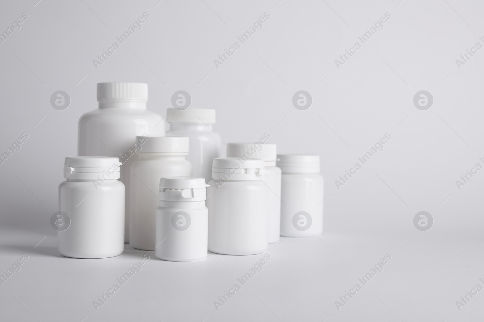 Photo of Many plastic medical bottles on white background, space for text